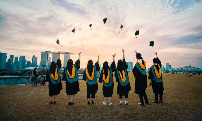 Graduating students in caps and gowns throwing their mortarboards